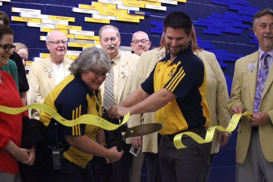 Kim Presko and Adam Taylor cut the banner in front of the wall.