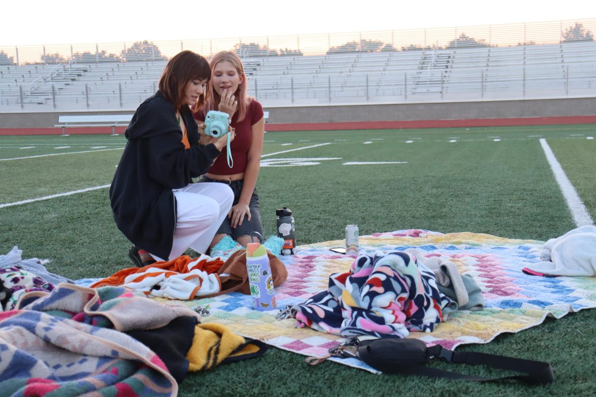 Seniors Alize Efta and Melody Bott look at a picture during the sunrise. Seniors participated in a Senior Sunrise on the first day of school.