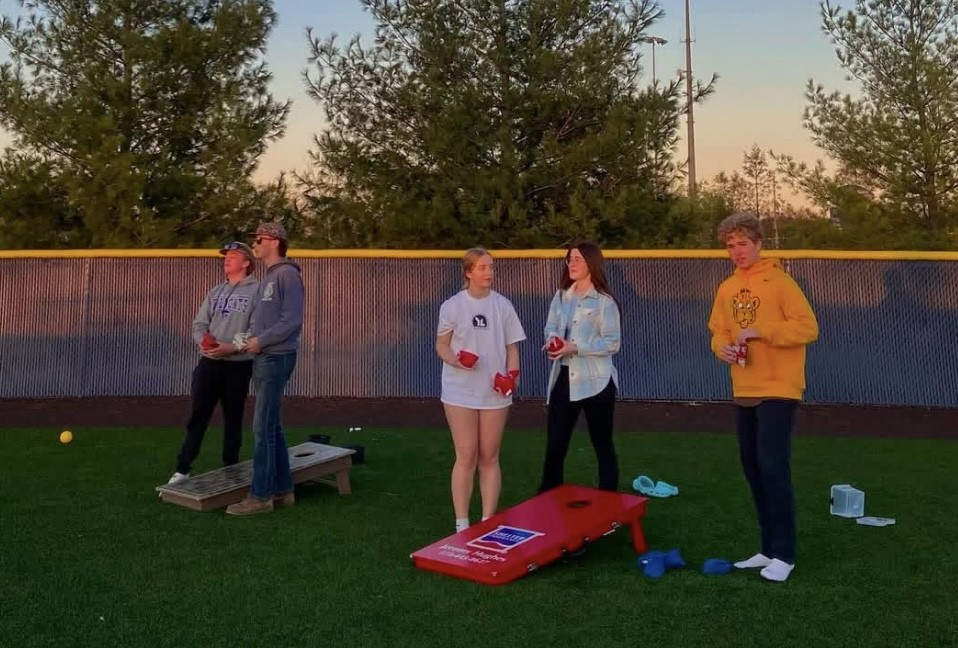 Carter Peck, Brandon Schoeneberg, Sarah Moore, Helena Duvnjak, and Grant Hughes participate in an intensive game of corn hole.