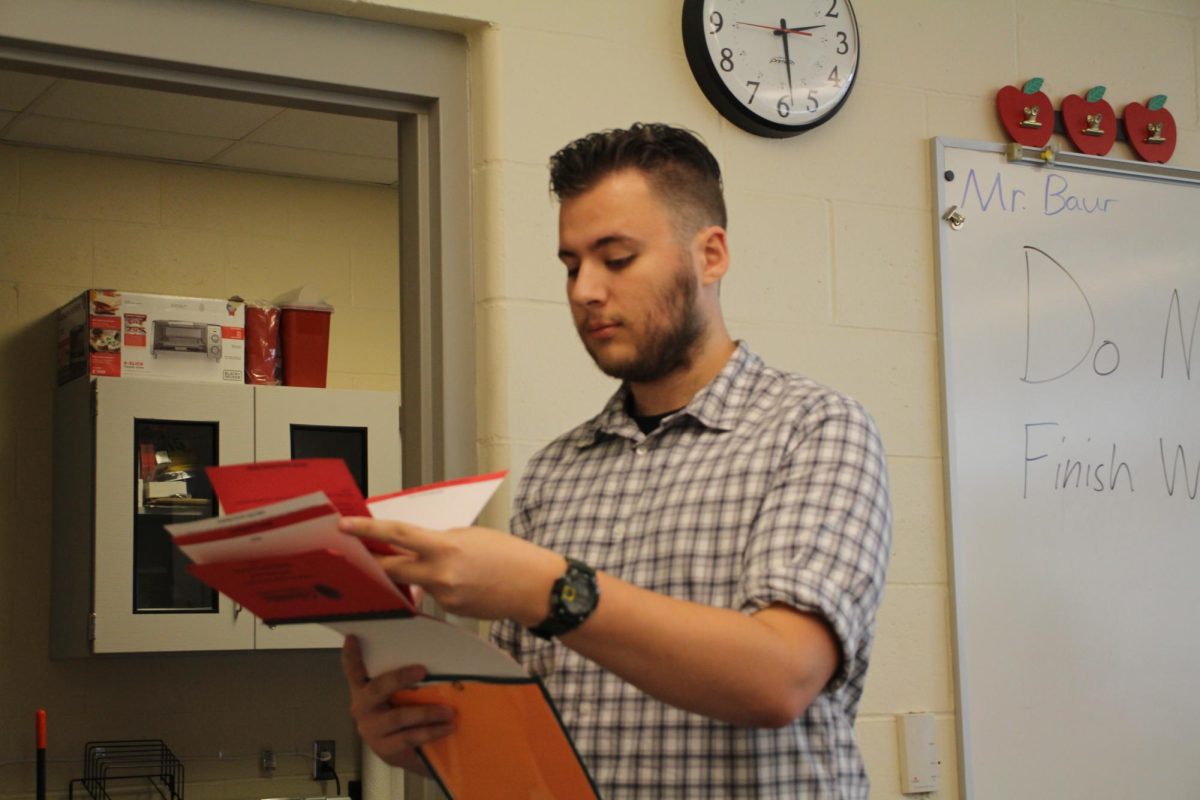 Science teacher Mr. Robert Baur reads to students from the flip guide for responding to emergencies. Every teacher at Battle has a flip guide in their classroom. 