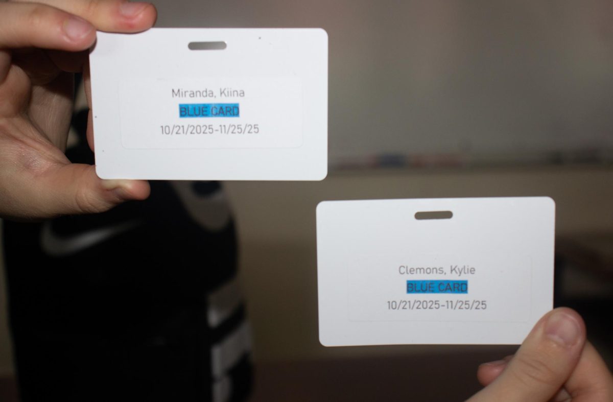 Students Kiina Miranda and Kylie Clemons hold up their blue cards.